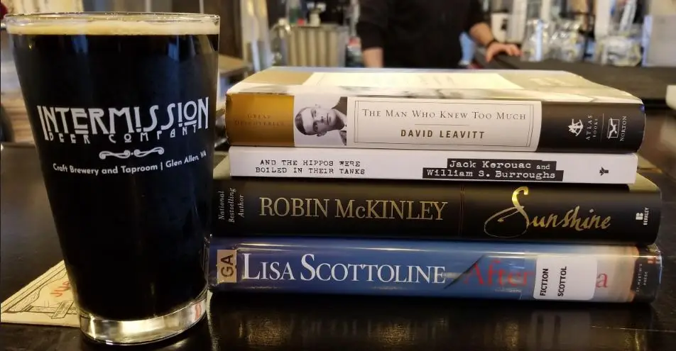 Books & Brews Book Promo. Event details: Every 1st & 3rd Sunday 4-6 PM at Intermission Beer Company, Brook Road. Reading, Drinking, Book Club. Pint size beer glass with a Porter. Books on display at a brewery for a "Books & Brews" event.